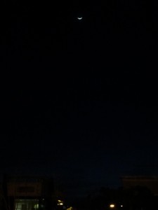 crescent moon at night, over office buildings