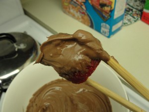using chopsticks to hold chocolate-dipped strawberry