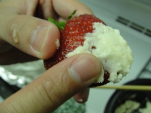 smearing white chocolate onto strawberry with fingers