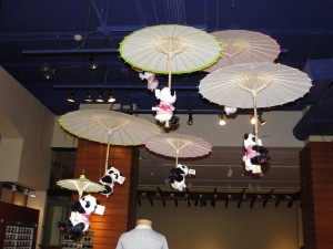 cherry blossom pandas hang on to umbrellas floating from the ceiling