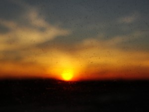 view of sunset from plane, through a dirty window