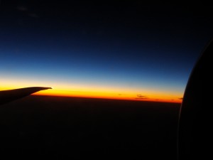 view of horizon from plane window with sun below horizon