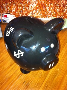 black oversized piggy bank with white dollar signs