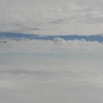 a sliver of blue sky shows between two layers of clouds outside airplane