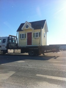 very small house on flatbed tow truck