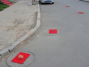 red paper held down by red bricks cover sewage caps