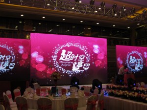 huge screen in ballroom of hotel with custom wedding theme logo displayed