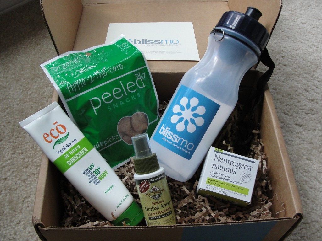 contents of blissmobox anniversary edition including eco logical sunscreen, peeled snacks apple-2-the-core, bates water filtration bottle with blissmo logo, all terrain insect repellent, and neutrogena naturals night cream