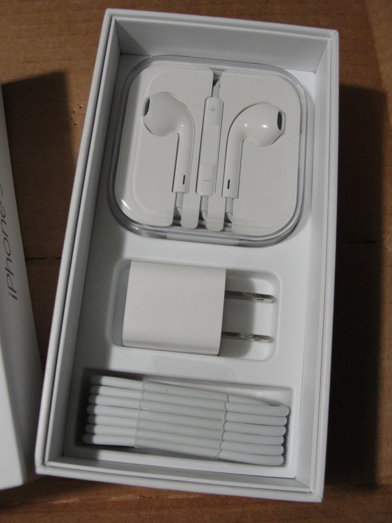 inside of iphone 5 box with accessories showing: earpods, charging cable, and charging plug