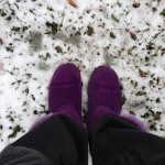 purple winter shoes against light layer of snow on grass