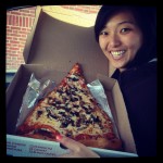 girl smiling with giant slice of jumbo pizza cheese with mushrooms