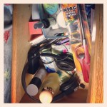 drawer filled with various skincare and home items including utility lighter and headphones
