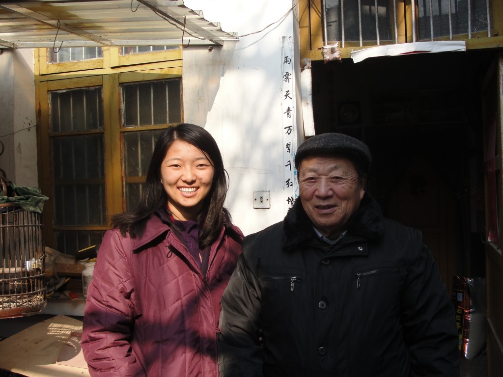 chinese granddaughter and grandfather standing outside doorway in winter