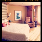 sunlight shining into nice hotel room with king bed and leather furnishings