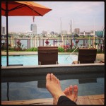 lounging by pool overlooking harbor with feet in shot