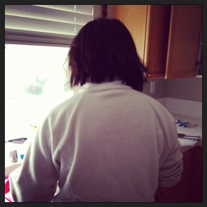 view of woman's back as she works in kitchen