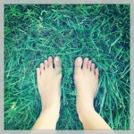 bare feet standing on lawn of green grass