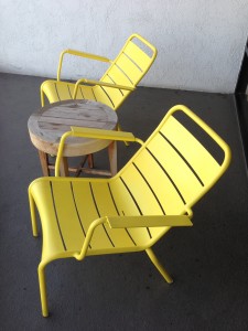 two yellow porch chairs and a wooden table on porch of room at hotel maya