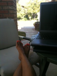 sitting on front porch with legs extended working on laptop