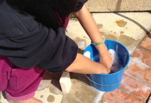cleaning with hands in blue metal bucket/pail filled with soapy water