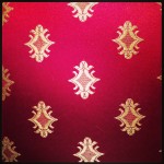 closeup of shiny red materials with complex gold pattern design