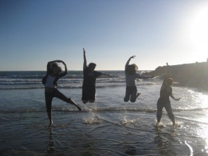four people jumping on beach spelling out rlcc
