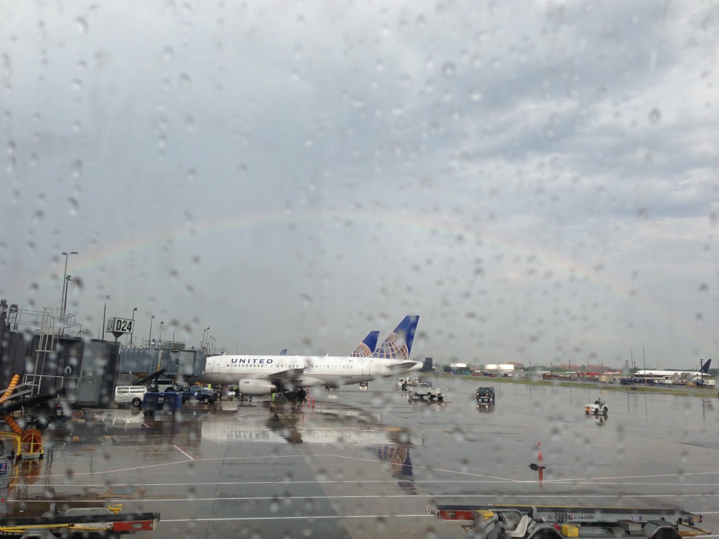 rainbow arching over planes at iad dulles international airport as seen from window seat of plane