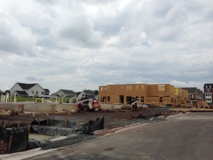 the three stages of the villas being built: foundation poured, frame up, and exterior completed