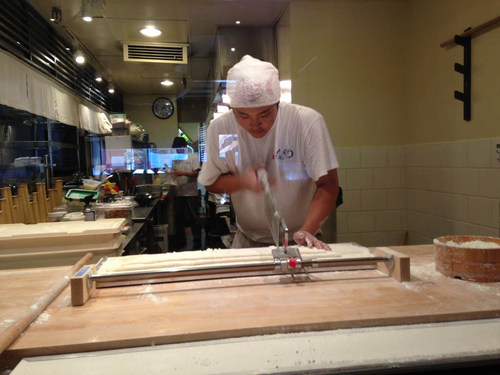 chef at japanese restaurant chopping line of udon noodles