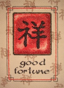 red, black, brown, and gold cross stitch pattern with chinese character and good fortune message