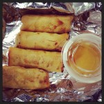 four vietnamese spring rolls with fish sauce on aluminum foil