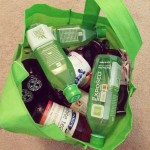 green reusable bag stuffed full of aloe and tea drinks