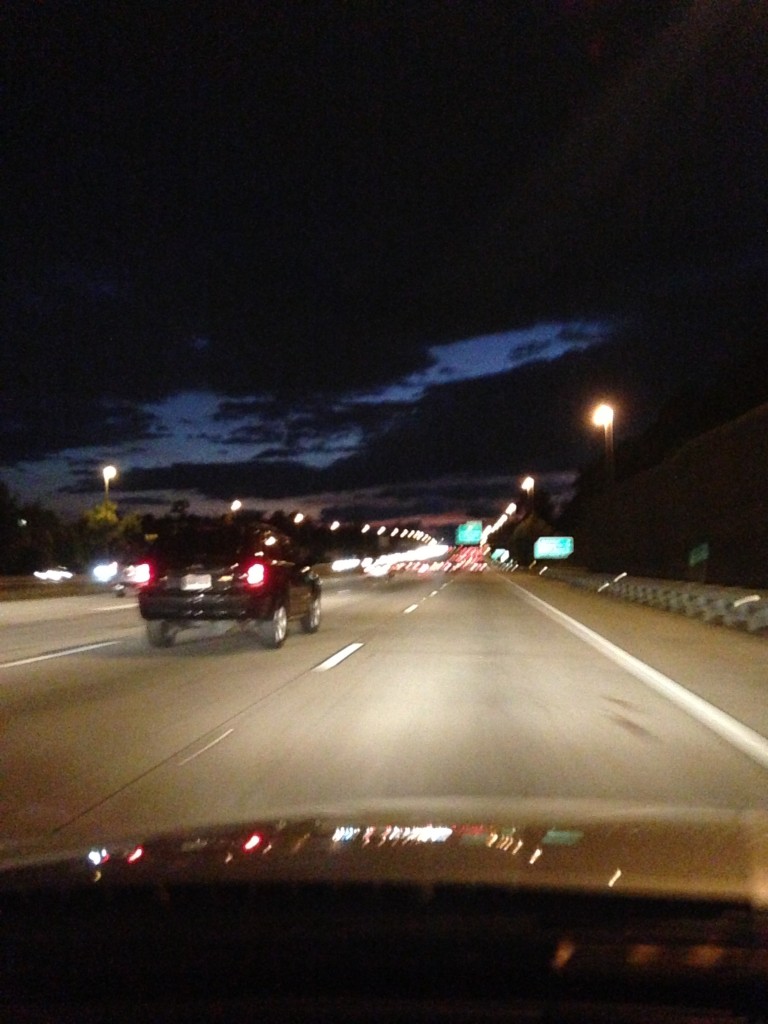 driving on freeway at night with lights dotting road and clouds darkening sky