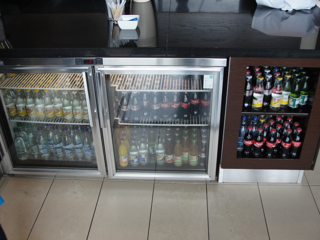 fridge and shelves with small glass bottles of sodas and drinks
