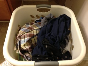 white sqaure laundry basket with clothes piled inside