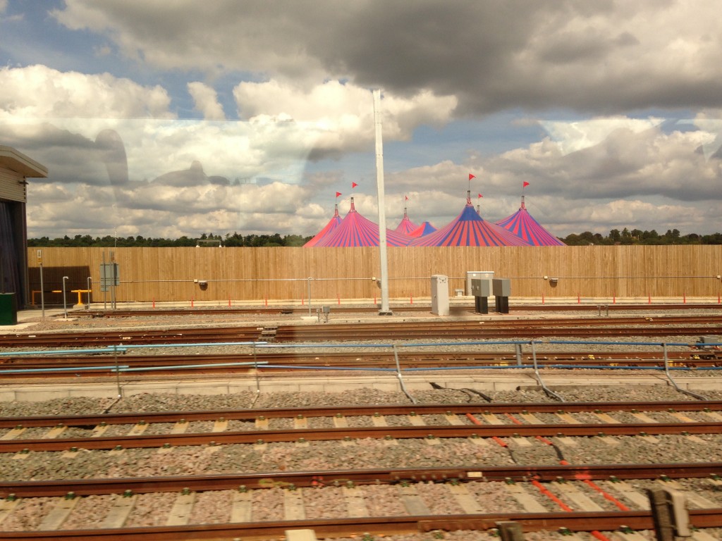 pink and blue striped circus tents beyond railroad tracks