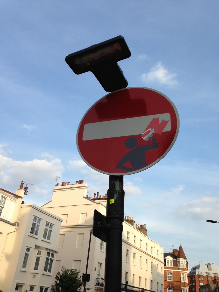 red and white street sign with sticker grafitti