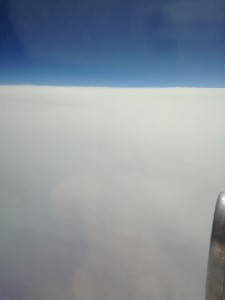 blue sky over thick layer of white clouds below plane