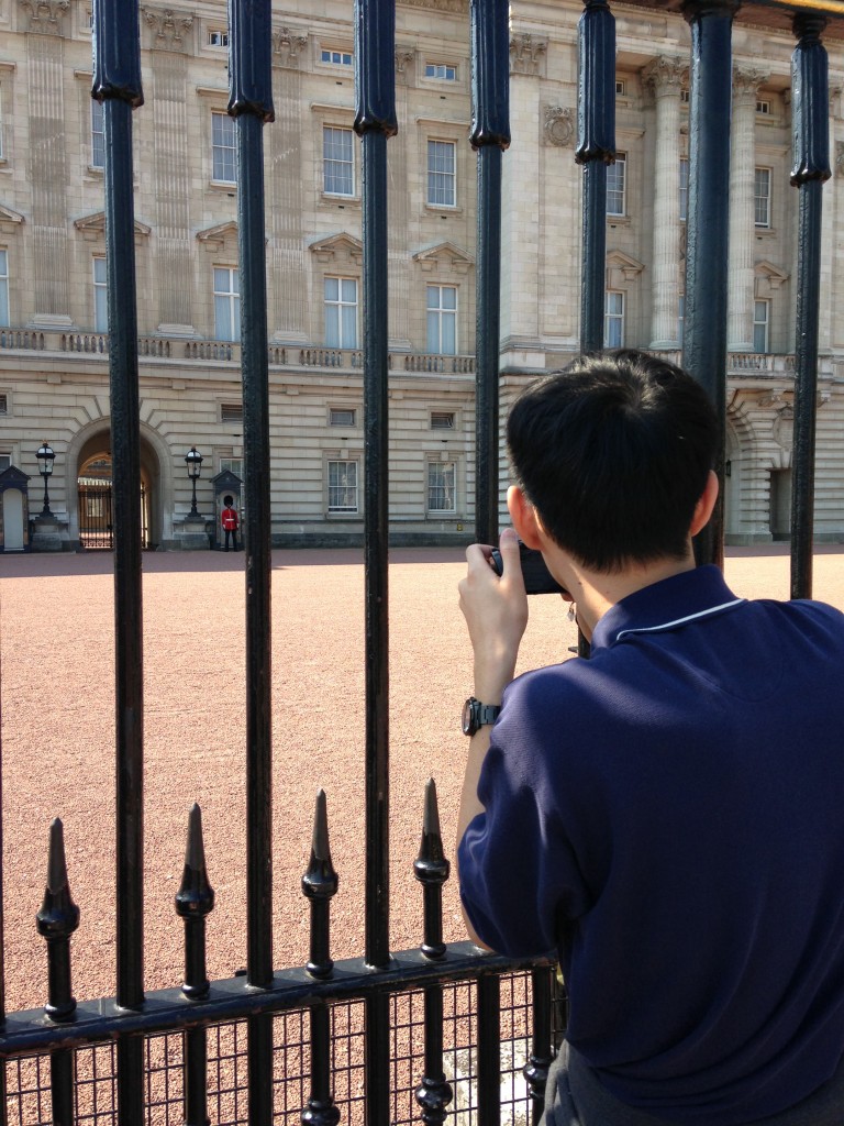 tourist taking picture of buckingham palace guard