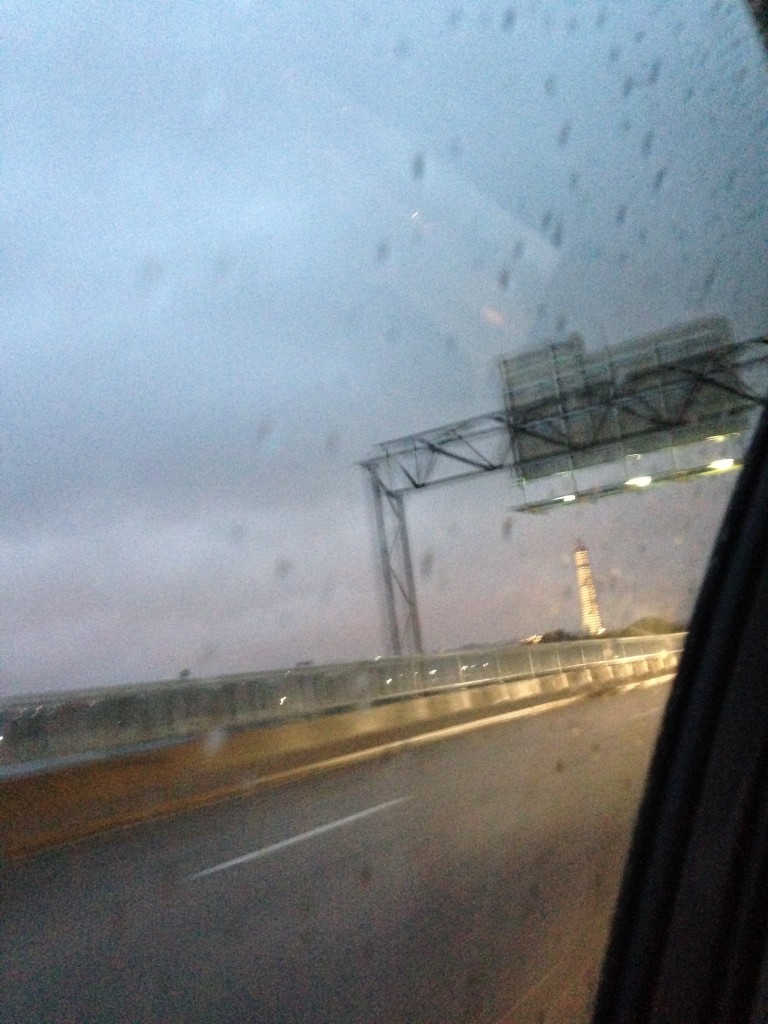 view of washington monument with lights lighting it up seen from car driving away in rain