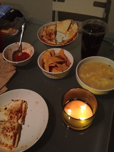 quesadillas, tortilla chips, salsa, egg drop soup, iced tea, and a candle on dinner table