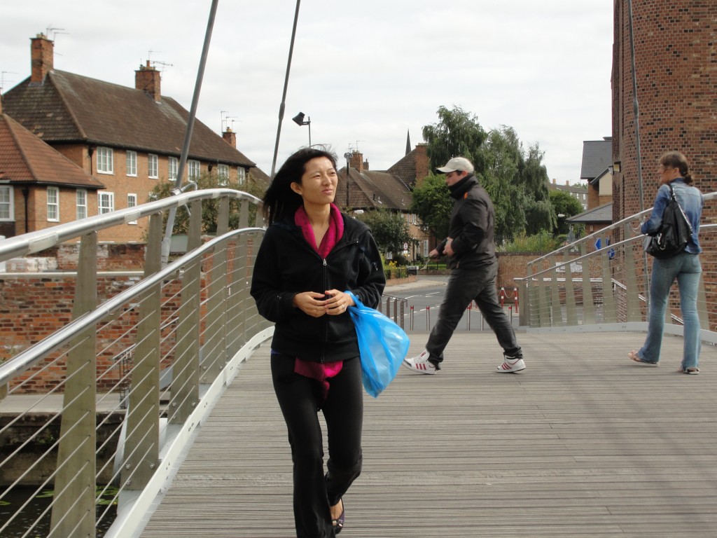 walking on bridge holding plastic bag with wind blowing hair around