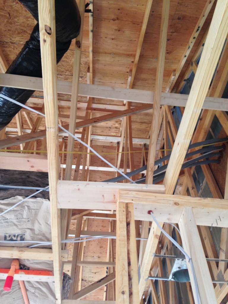 view upwards of wood beams supporting interior of condo frame mid-construction