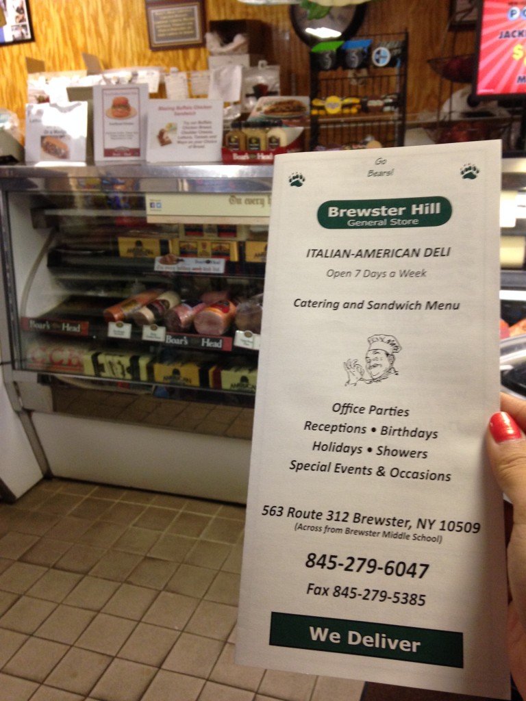 holding up menu for brewster hill general store inside store by deli