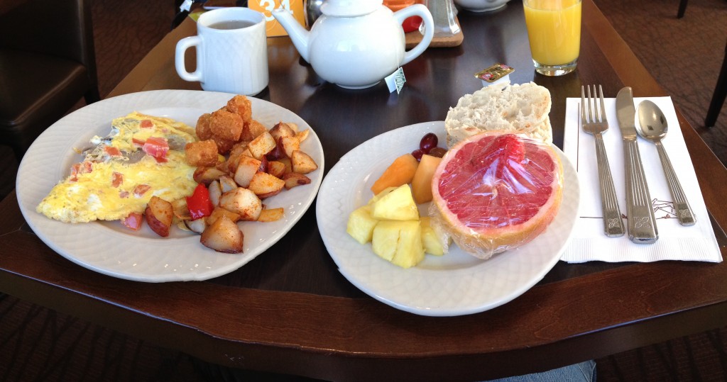 panoramic of hilton garden inn breakfast with omelette, potatoes, pineapple, cantaloupe, grapes, grapefruit, english muffin, tea, and orange juice