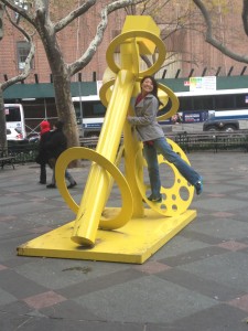 posing on bright yellow street art sculpture in park in nyc