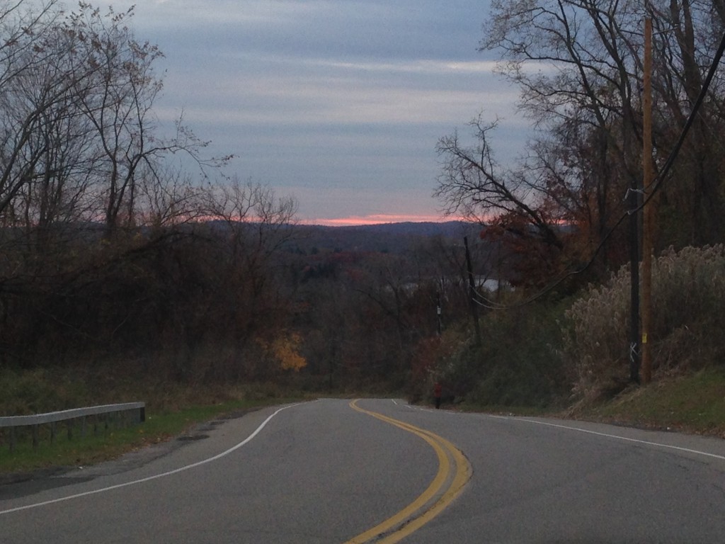 sunset and lake in distance viewed from brewster hill with steep road going down