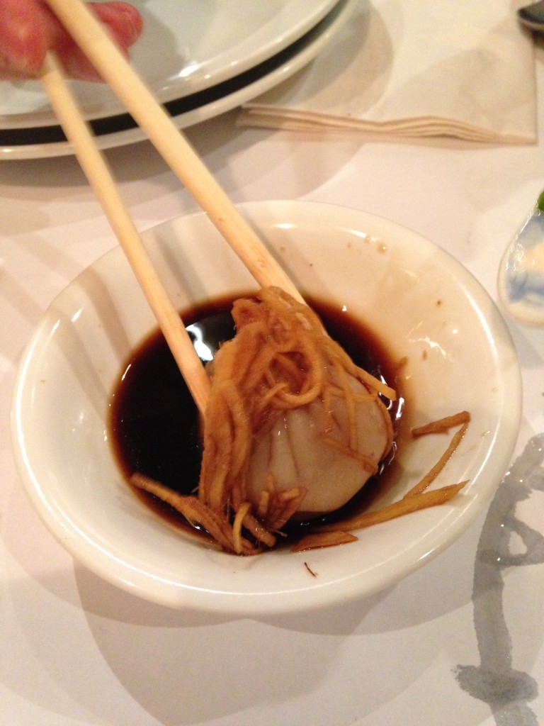 xiao long bao juicy pork dumpling in vinegar sauce with ginger slices covering it