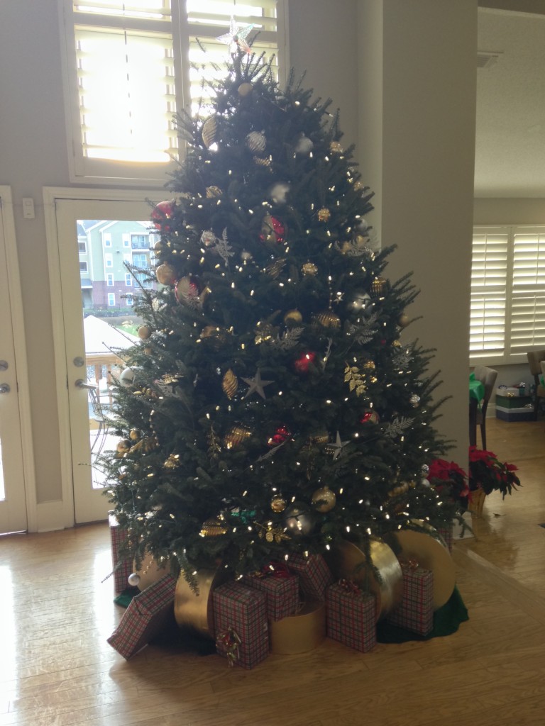 christmas tree with presents underneath set up at rental office of apartment complex