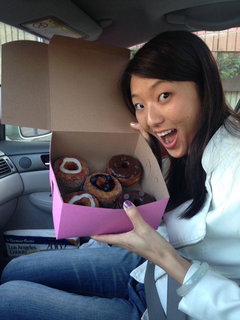 excited girl holding up box of cronuts in car